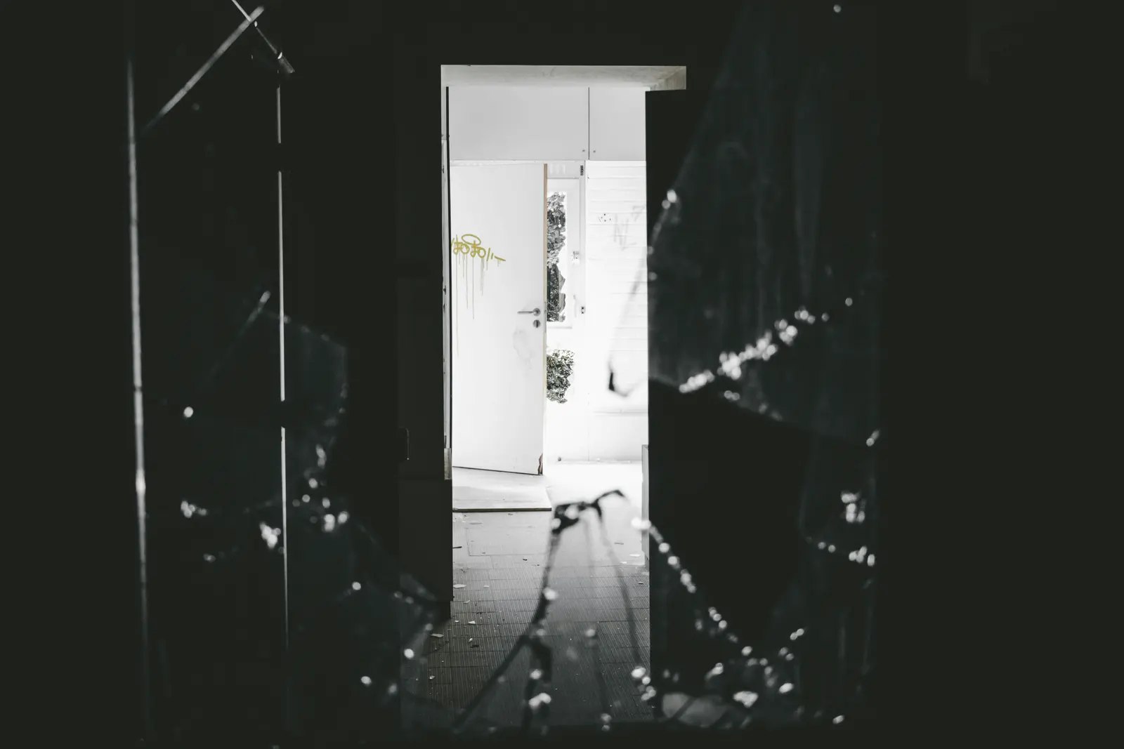 Zerbrochenes Fenster und offene Tür in einem leeren Gebäude